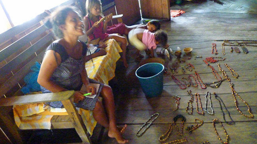 Smiling woman and her family with display of jewellery laid out on wooden floor